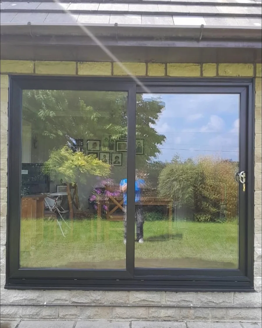 Wide black-framed sliding door set into a stone wall