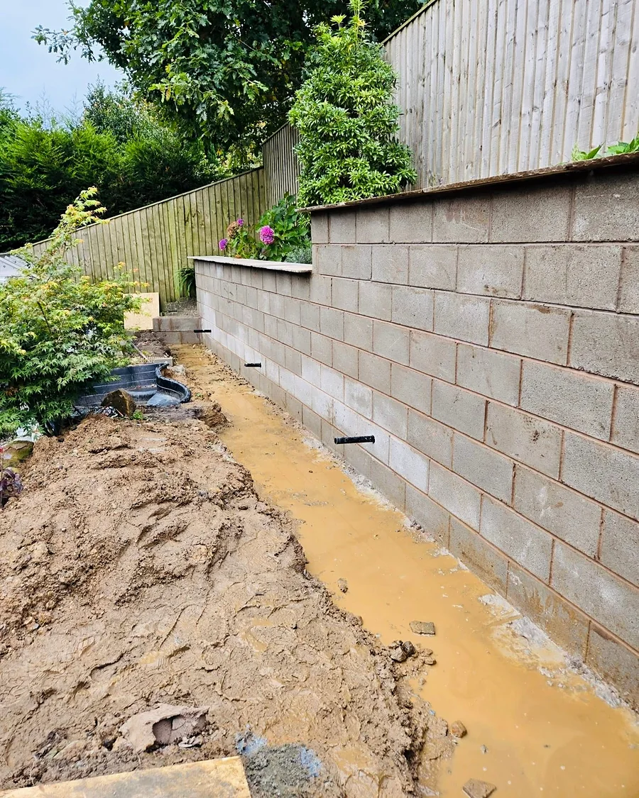 Concrete block retaining wall going up along the bottom of a sloping garden