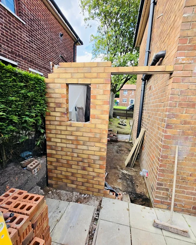 Side extension going up in brick, with the window opening formed