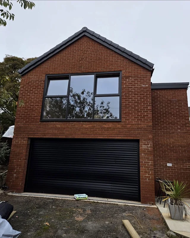 Brick garage extension with a black roller door, Lobden