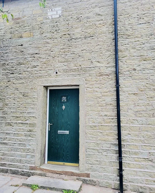 Repointed stone house front with a green door, Whitworth